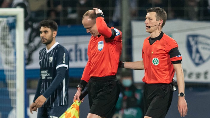 Der Schiedsrichterassistent Christian Gittelmann reibt sich den Kopf nachdem er von einem Bierbecher der Bochum-Fans getroffen wurde