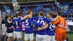 Schalke Spieler stehen im Stadion vor der Fankurve