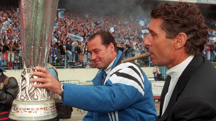Schalke-Trainer Huub Stevens hält den UEFA-Pokal in der Hand, neben ihm der Manager Rudi Assauer