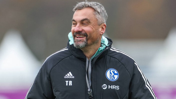 Schalkes Trainer Thomas Reis lacht während einer Einheit am Seitenrand.