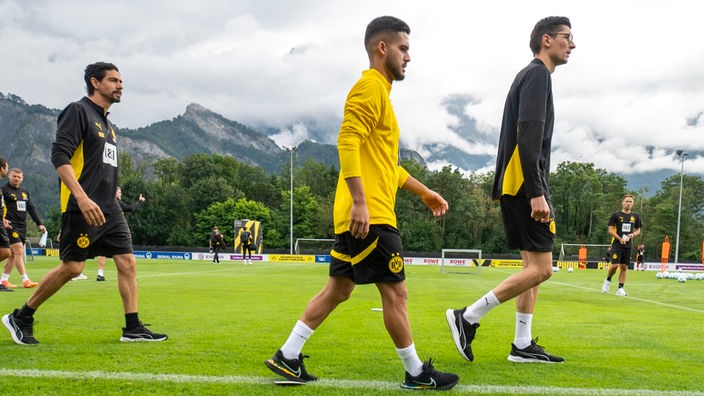 Yan Couto (Mitte) betritt den Trainingsplatz des BVB und geht zum Fitnesszelt.