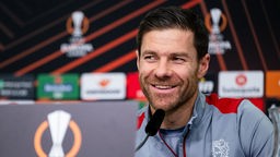 Leverkusens Trainer Xabi Alonso lächelt während der Pressekonferenz.
