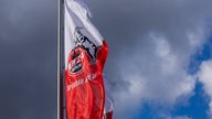 Eine Fahne mit dem Logo des Fußball-Bundesligisten 1. FC Köln weht vor dunklen Wolken