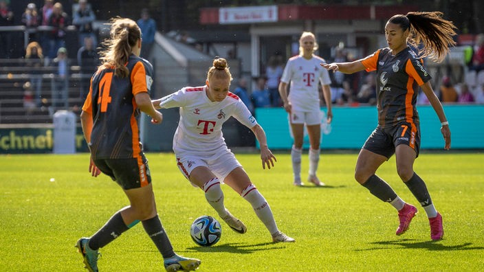 Laura Vogt (Mitte) vom 1. FC Köln geht gegen zwei Duisburgerinnen ins Dribbling