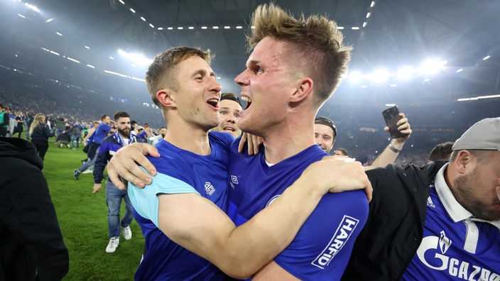Nach Spielschluss bejubelt Schalke-Spieler Maris Bülter mit Fans den Aufstieg