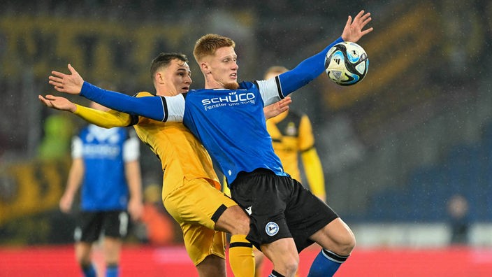 Fußballprofi Leon Schneider (r.) von Arminia Bielefeld nimmt im Drittliga-Siel gegen Dynamo Dresden den Ball an