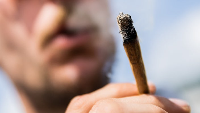 Ein Mann raucht einen Joint.