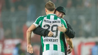 Preußen Münsters Lukas Frenkert (vorne) und Trainer Sascha Hildmann jubeln über das späte 1:1 beim KSC.