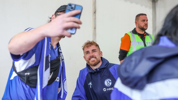 Ein Schalke-Fan macht ein Foto mit Schalke-Spieler Ralf Fährmann