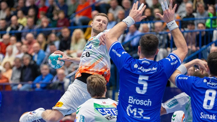 Handballspieler Philipp Weber (l.) vom SC Magdeburg steigt gegen die Abwehr des TBV Lemgo Lippe hoch