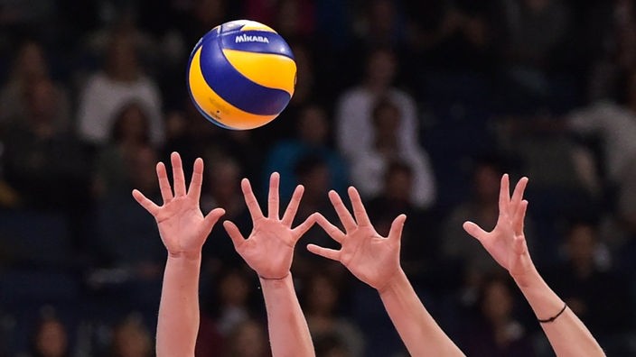 Hände versuchen einen Volleyball zu blocken (Symbolbild)