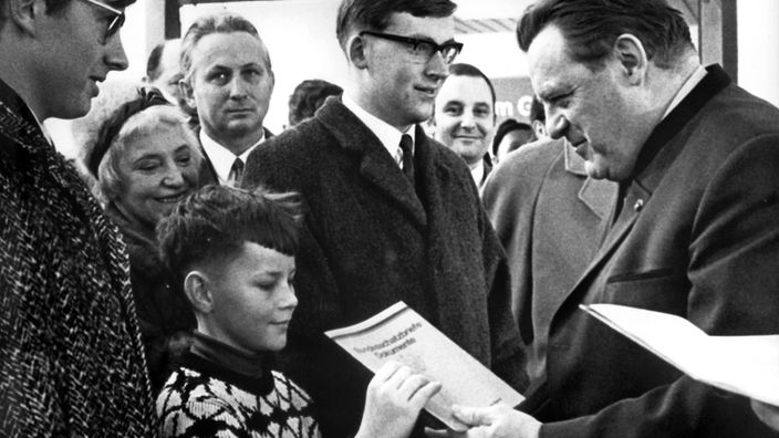 Bundesfinanzminister Franz Josef Strauß (r) schenkt am 30. Dezember 1968 in Rott am Inn dem neunjährigen Jacob Englhauser (l) einen Bundesschatzbrief.