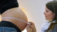 Hebamme misst Bauchumfang einer Schwangeren 