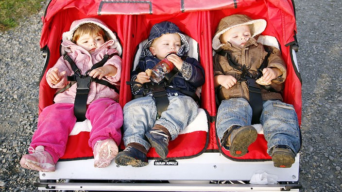 Drei Kinder im Kinderwagen