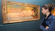 Eine Besucherin betrachtet ein Gemälde von Pierre-Auguste Renoir 