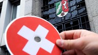 Eine Hand hält vor dem Eingang des NRW-Finanzministeriums in Düsseldorf eine CD mit einem aufgedruckten Schweizerkreuz