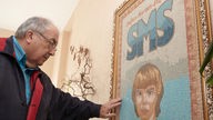 Emil Morsch, Vorstandsvorsitzender der Stefan-Morsch-Stiftung, steht vor einem Mosaik, das seinen verstorbenen Sohnes zeigt