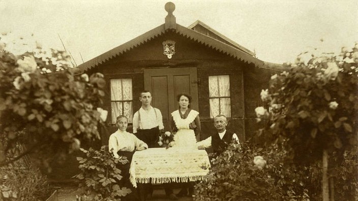 "Familie Rauscher" sitzt um das Jahr 1925 am Tisch vor ihrem Wochenendhäuschen im Schrebergarten 