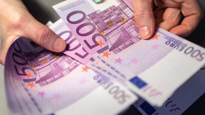 Mitarbeiterin einer Bank zählt 500-Euro-Scheine ab