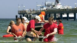 DLRG-Rettungschwimmer demonstrieren vor der Binzer Seebrücke die Rettung eines Badegastes