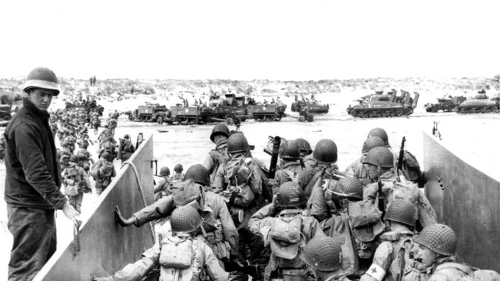 Soldaten der alliierten Truppen verlassen während des Zweiten Weltkriegs ein Landungsboot an der Küste der Normandie