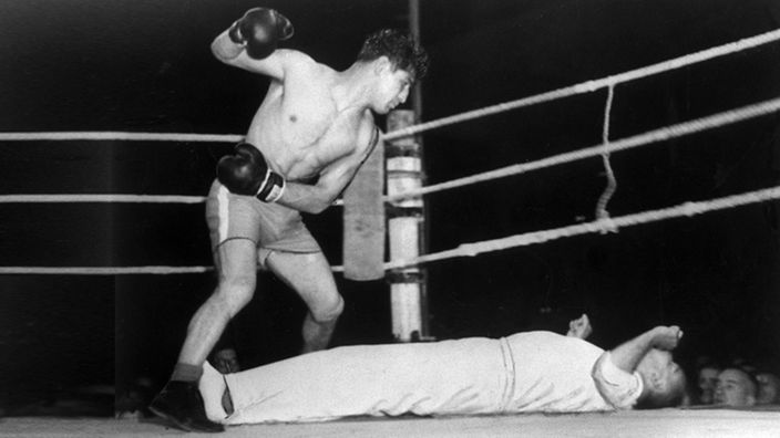 Boxer Peter Müller mit erhobener Faust über dem am Boden liegenden Ringrichter Pippow