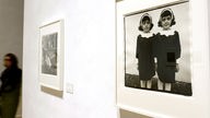 Eine Frau geht am Donnerstag (21.06.2012) in der Ausstellung "Diane Arbus" im Martin-Gropius-Bau in Berlin am Bild "Identische Zwillinge" vorbei.