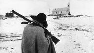 Ein in eine Decke gehüllter indianischer Wachtposten patrouilliert im März 1973 mit seinem geschulterten Gewehr in Wounded Knee