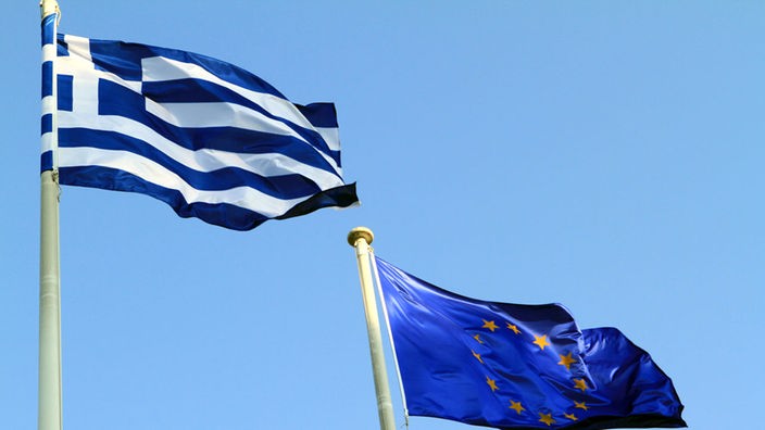Die Nationalflagge Griechenlands und die Flagge der EU vor blauem Himmel