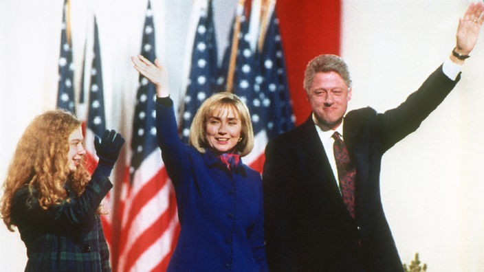 US-Präsident Bill Clinton mit Frau Hillary und Tochter Chelsea winkend vor US-Flaggen 