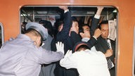 Personal der U-Bahn Tokio schiebt Passagiere in überfülltes Abteil