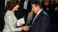 Die schwedische Königin Silvia (l) und Außenminister Sigmar Gabriel (SPD) begrüßen sich am 26.09.2017 vor Beginn der Verleihung des Theodor-Wanner-Preises im Allianz-Forum in Berlin.
