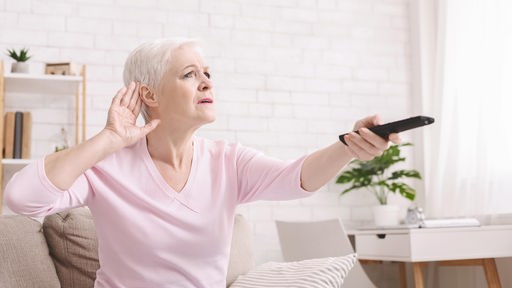 Ältere Frau, die ihre Hand hinter dem Ohr hält, um besser zu hören