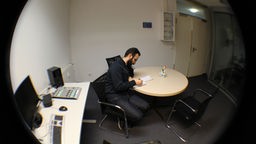 Ein Teilnehmermacht sich am Tisch im Studio Notizen