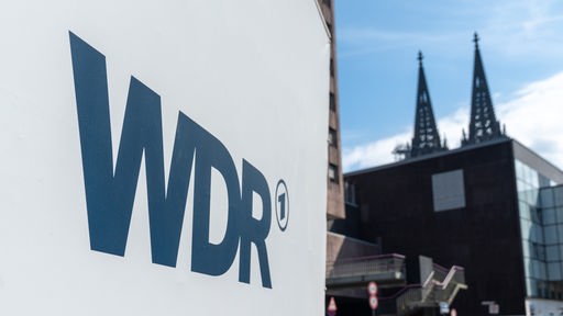 LKW mit WDR-Logo auf der Seitenplane, rechts im Hintergrund ist der Kölner Dom.