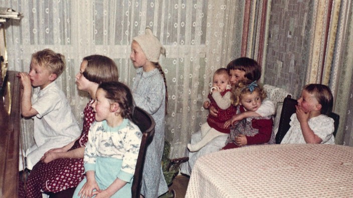 Eine Gruppe Kinder sitzt im Schlafanzug vor dem Radio