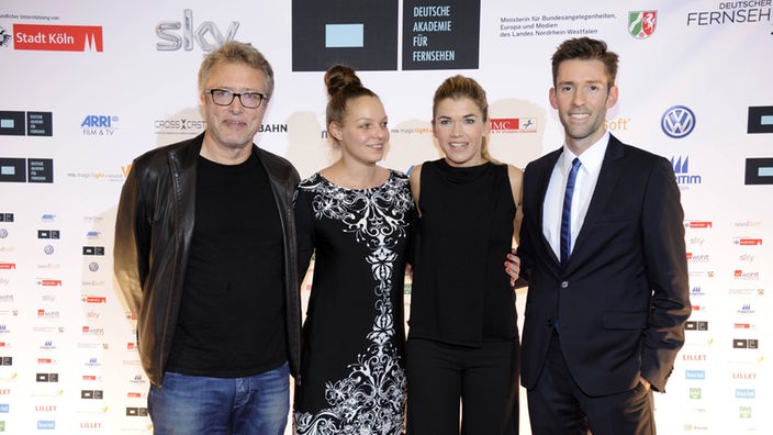 Anke Engelke steht vor Sponsorenwand zusammen mit zwei Männern und einer Frau
