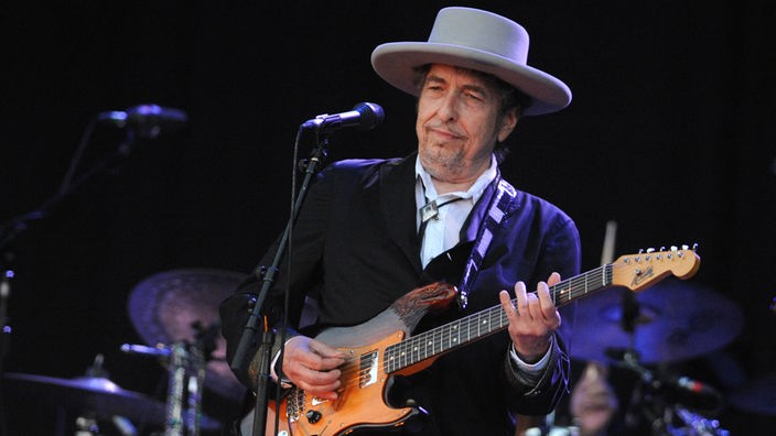 Bob Dylan mit Gitarre auf der Bühne.