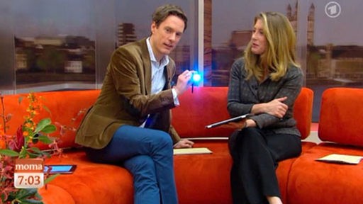 Sven Lorig leuchtet Comoderatorin Anne Gesthuysen mit der Taschenlampe