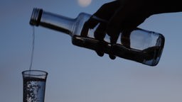 Das Bild zeigt wie ein alkoholisches Getränk in ein Glas eingeschüttet wird
