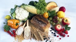 Das Bild zeigt verschiedene gesunde Nahrungsmittel, wie Obst, Gemüse und Getreide.