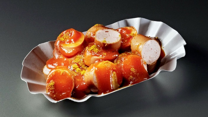 Das Bild zeigt eine Currywurst in einer Pappschale.