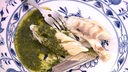 Loup de mer in der Salzkruste mit Petersilien-Knoblauch Öl auf einem Teller angerichtet