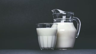 Das Bild zeigt ein Glas und eine Karaffe mit Hafermilch.