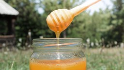 Honig fließt in ein Glas.