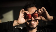 Mann hält sich zwei Tomaten vor die Augen