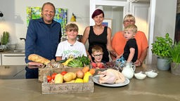 Das Foto zeigt Fernsehkoch Björn Freitag mit Familie Welz aus Bottrop in einer Küche. 