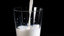 Das Bild zeigt, wie Milch in ein Glas gegossen wird.