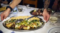 Das Bild zeigt eine Person, die Essen im "Zé da Mouraria" in Lissabon serviert. 