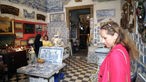 Das Bild zeigt Tamina Kallert, die einen Antiquitätenladen betritt.